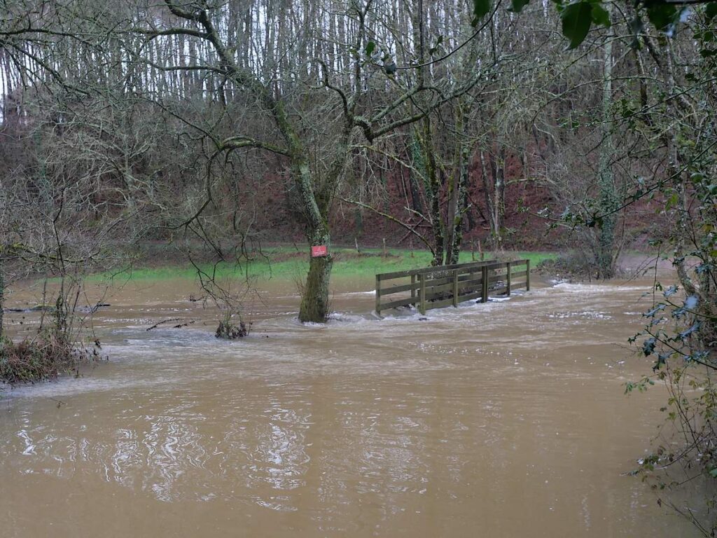 l'eau tourbillonne et dépasse le pont du gué de Trohinat