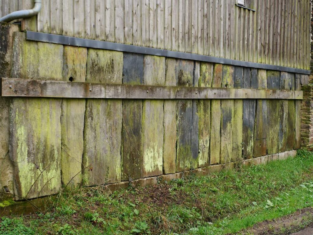 Soubassement de grands palis sur une grange ancienne transformée en habitation