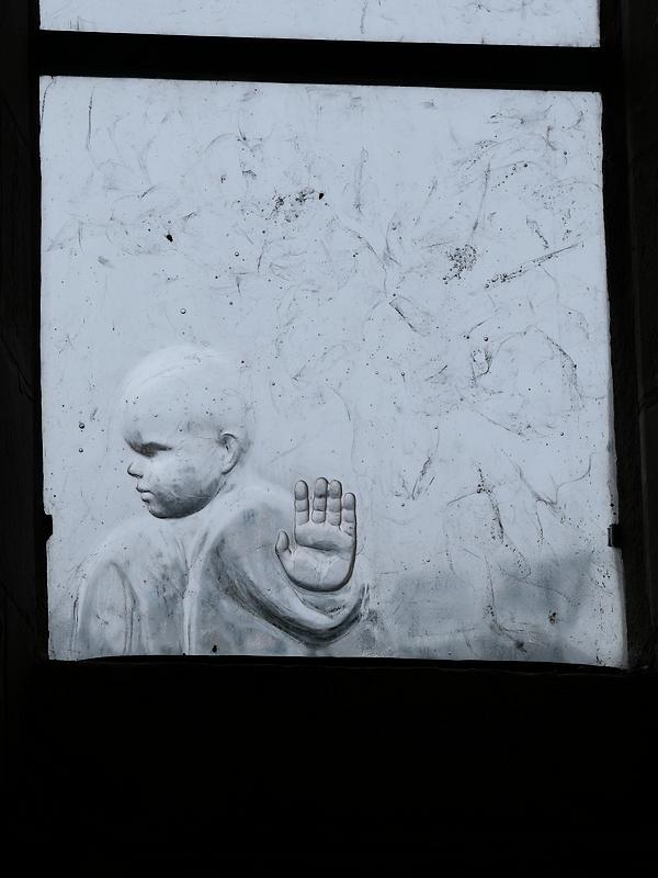 Un bébé sur un vitrail de l'abbaye de Saint-Gildas-des-bois tend le bras en signe d'opposition