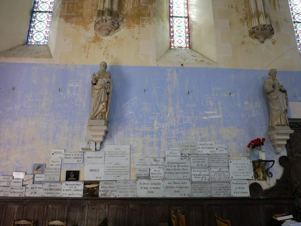 Un mur avec des graffitis et des ex voto